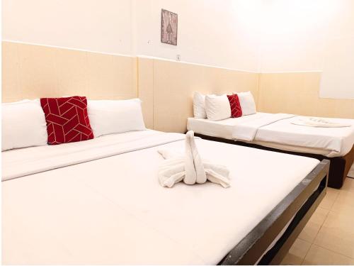 two beds in a room with white sheets at Invito Guesthouse in Sihanoukville