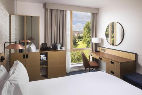 a hotel room with a bed and a desk and a window at Hilton Garden Inn Bristol City Centre in Bristol
