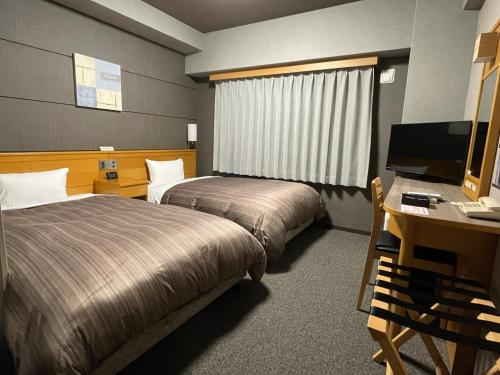 a hotel room with two beds and a desk and a computer at Hotel Route-Inn Yukuhashi in Yukuhashi