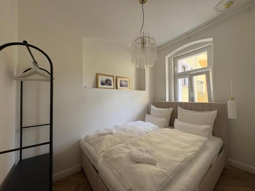 a bedroom with a bed with white sheets and a chandelier at Monte-Rosa in Karlovy Vary