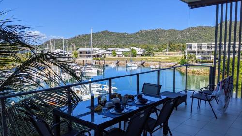 a table on a balcony with a view of a marina at Blue on Blue Apartment 932 in Nelly Bay
