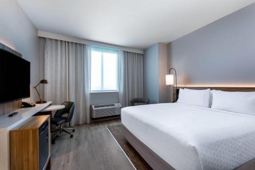 a hotel room with a bed and a desk and a television at Wyndham Garden Miami International Airport in Miami