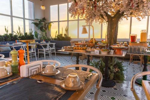 a restaurant with tables with food and a tree at Faranda Collection Barranquilla, a member of Radisson Individuals in Barranquilla