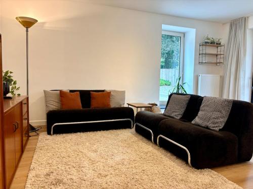 a living room with two black couches and a rug at Verblijf in het Pajottenland in Gooik