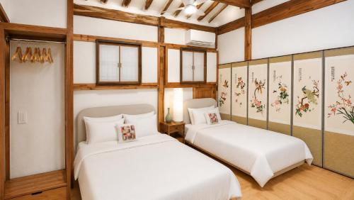 two beds in a room with wooden ceilings at HAEMIL Hanok 해밀한옥 in Seoul
