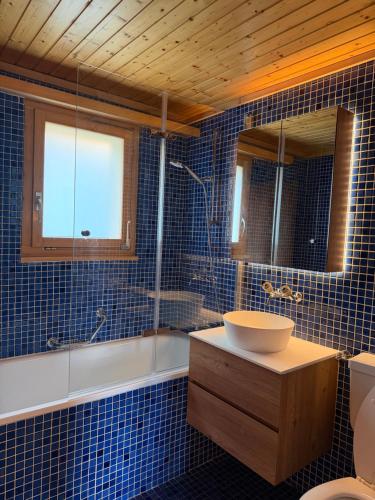 a blue tiled bathroom with a sink and a tub at Chalet Montis in Bellwald