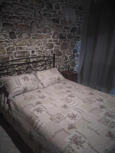 a bed in a room with a stone wall at Riverbird House in Kymi