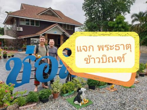 two people standing in front of a sign in front of a house at ช่อฟ้า การ์เด้น in Phrae