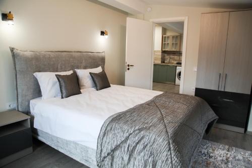 a bedroom with a large white bed and a kitchen at Ъгловата къща in Lovech