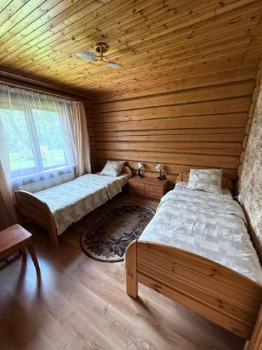 a bedroom with two beds in a wooden cabin at Pakrasti in Svente