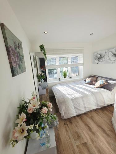 a bedroom with a bed and flowers on a table at Kents Hill Studio in Woolstone