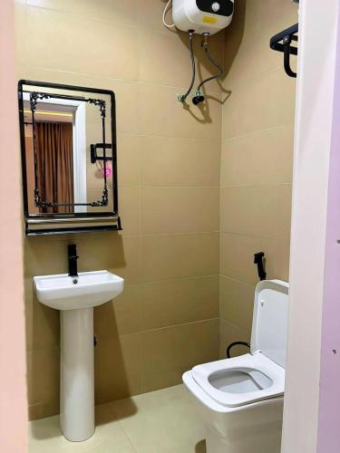 a bathroom with a toilet and a sink and a mirror at Ciamo Hotel in Ikeja