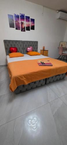 a bed with an orange comforter in a room at Maca apartman 23 in Petrovaradin