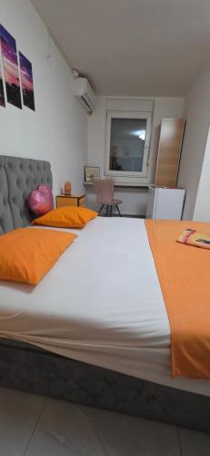 a large white bed with orange pillows in a room at Maca apartman 23 in Petrovaradin