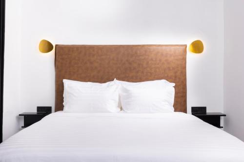 a bed with white pillows and a wooden headboard at H34 Boutique Hotel & Spa by the sea of Nahariya in Nahariyya