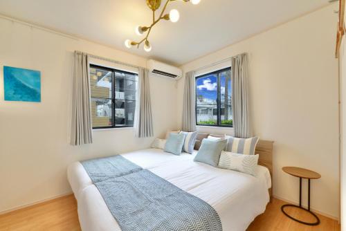 a bedroom with a large white bed with two windows at 北谷町港2 in Chatan