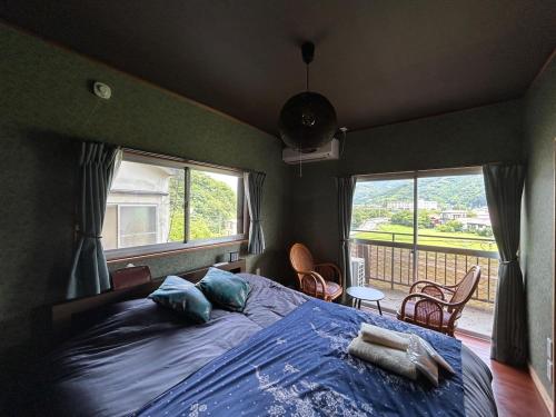 a bedroom with a bed with a blue comforter and two windows at Kawazu Sakura-so in Kawazu