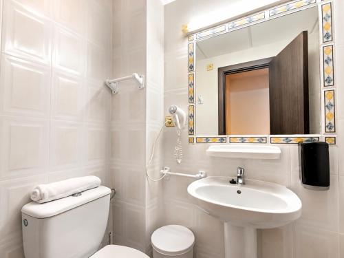 a bathroom with a toilet and a sink and a mirror at Hotel Bossh Lido in Benidorm