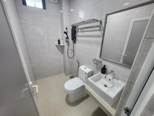 a white bathroom with a toilet and a sink at Hotel O Rosegold Garden in Kuantan