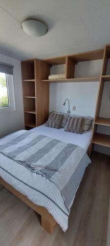 a bedroom with a large bed with wooden shelves at Veluwemeer Lodge in Elburg