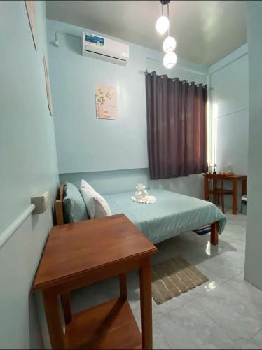 a room with a bed and a table and a window at Mahika Guest House Siquijor in San Juan