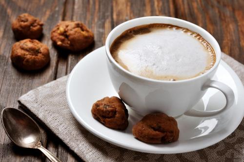 a cup of coffee on a plate with cookies on a table at Hapimag Ferienwohnungen Braunlage in Braunlage