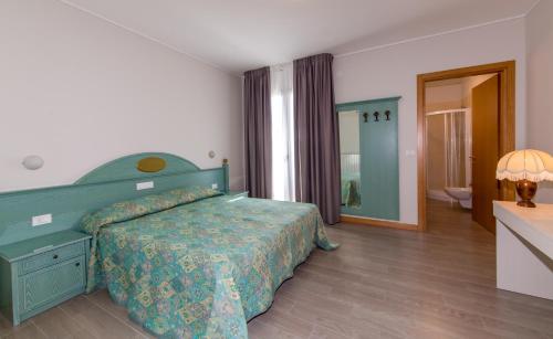 1 dormitorio con cama verde y baño en Residence California, en Lido di Jesolo