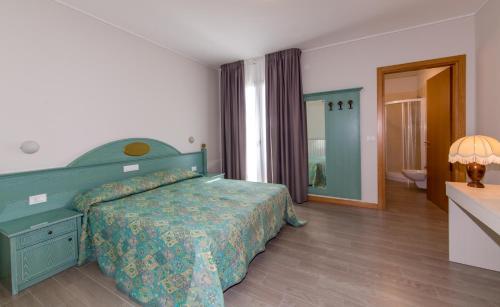 a bedroom with a green bed and a bathroom at Residence California in Lido di Jesolo