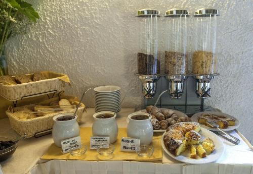 a table topped with plates of pastries and cups of coffee at Hotel Colle Etrusco Salivolpi in Castellina in Chianti