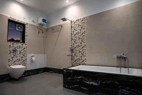 a bathroom with a bath tub and a toilet at Jowar Hotel & Resort in Digha