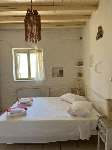 a bedroom with a bed with white sheets and a window at Paros Sunset Villas PSV & PSV2 in Parikia