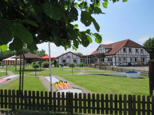 a playground in front of a building with a fence at Premium-Ferienhaus Ingrid Marie im Feriendorf Altes Land an der Elbe in Hollern-Twielenfleth