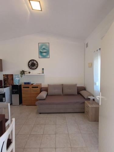 a living room with a couch and a clock on the wall at Apartman Mivela in Vir