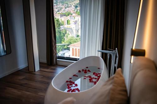 a white chair with red flowers in a room with a window at Villa Anri in Mostar