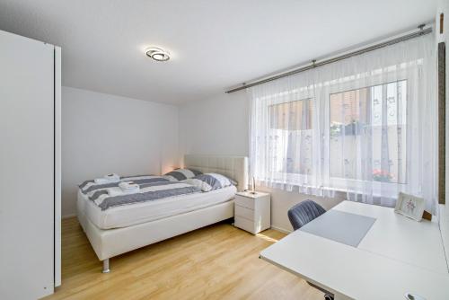 a white bedroom with a bed and a table at Apartment Dußlingen in Dußlingen