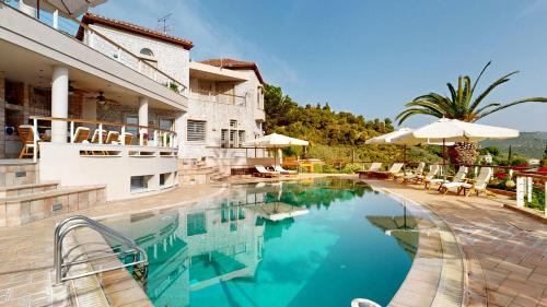 a swimming pool with chairs and umbrellas next to a building at Epidavros Villas - Gardenia Garden Retreat with Shared Pool in Nea Epidavros
