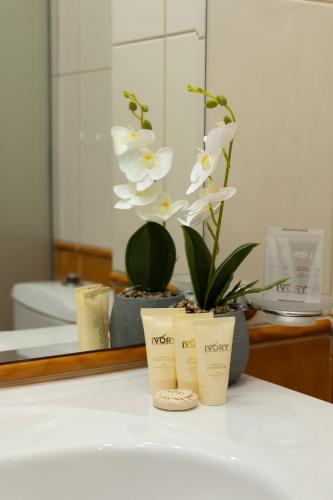 a bathroom counter with a vase with white flowers at Hotel Trezor in Varna City