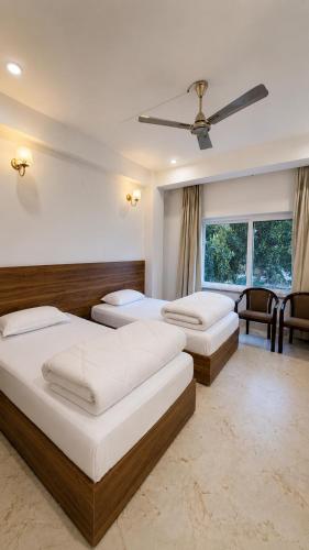 a bedroom with two beds and a ceiling fan at Vortex Suites in Guwahati