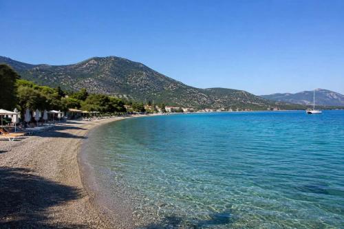 a beach with blue water and mountains in the background at Epidavros Villas, Thymari Garden & Seaview Retreat in Nea Epidavros