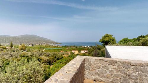 a stone wall with a view of a city at Epidavros Villas, Thymari Garden & Seaview Retreat in Nea Epidavros
