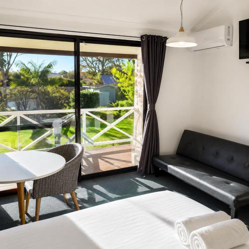 a room with a couch and a table and a balcony at Karri Forest Motel in Pemberton