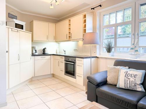 a kitchen with white cabinets and a black couch at Ferienhaus Meeresrauschen in Groß Kirr