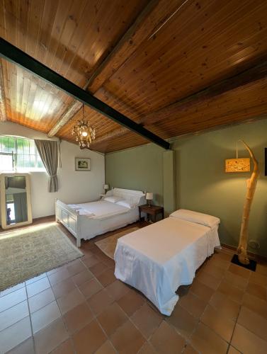 a bedroom with two beds and a wooden ceiling at Giardino Antico in Montecarotto