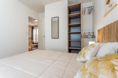 a white bedroom with a large bed and a book shelf at Gite les Mazets du Rouret in Saint-Christol-lès-Alès
