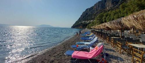 a beach with chairs and umbrellas and the water at Epidavros Villas - Dafni Stone & Garden Retreat in Nea Epidavros