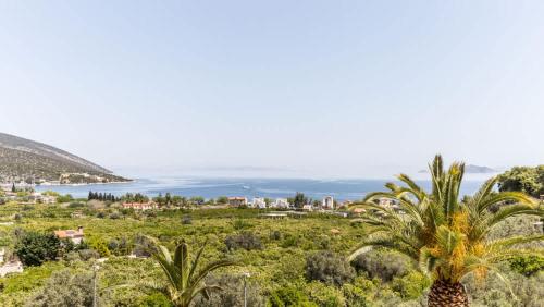 a view of a town with palm trees and the ocean at Epidavros Villas - Dafni Stone & Garden Retreat in Nea Epidavros