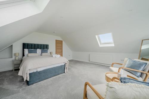 a white bedroom with a bed and a chair at Seaddler in Holyhead