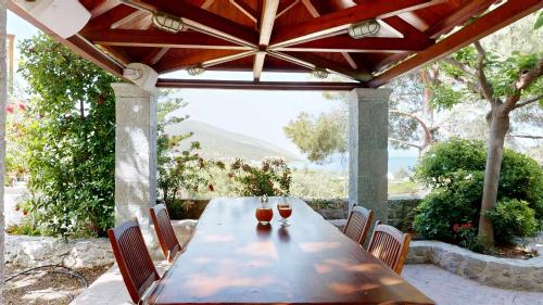 a wooden table with two glasses of wine on a patio at Epidavros Villas Voukamvilia Retreat, Shared Pool in Nea Epidavros