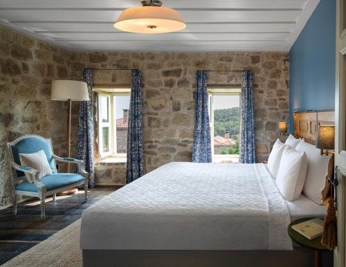 a bedroom with a bed and a chair and windows at İda Blue Adatepe in Küçükkuyu