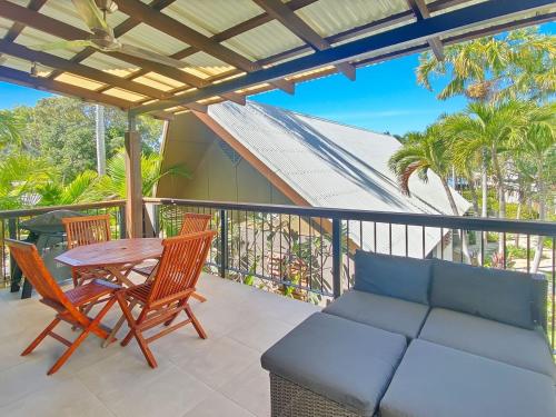a patio with a couch and chairs on a balcony at Pure Magnetic Villa 9 in Nelly Bay